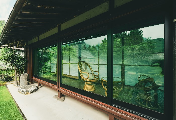 縁側越しに庭を眺めるラタンチェアのくつろぎスペース