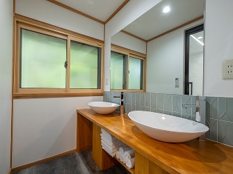 木製カウンターに2つの洗面ボウルが並ぶ明るい洗面スペース