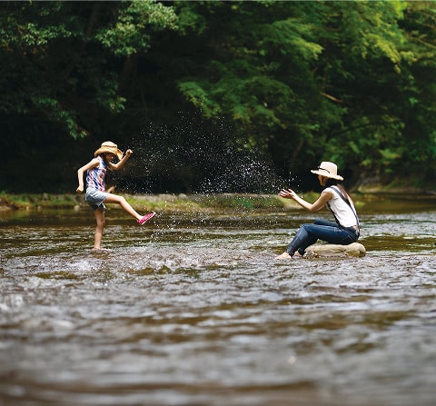 川の中で水遊びを楽しむ親子の様子