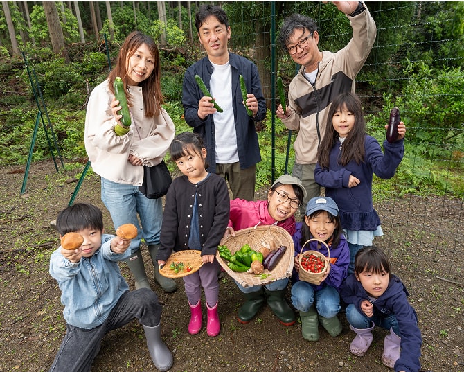 採れたての野菜を手に、収穫体験を楽しむ家族と子どもたち