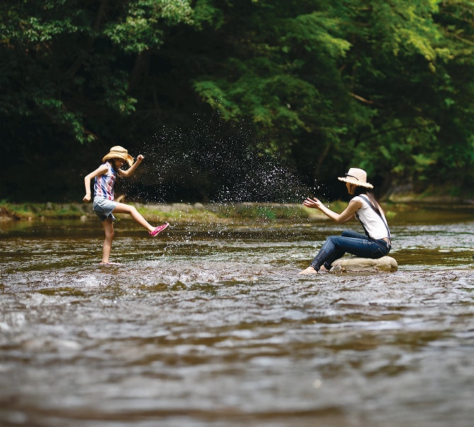川の中で親子が水しぶきを上げて遊んでいる様子