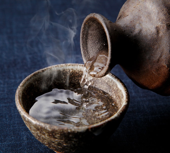 湯気の立つ熱燗を徳利から猪口に注ぐ様子